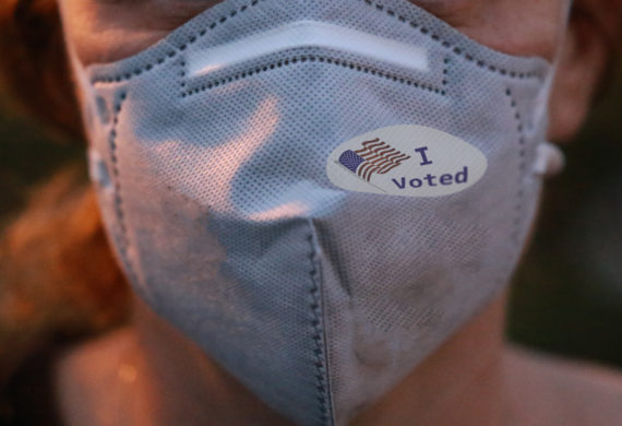 Selective focus on I Voted sticker with USA flag on face mask.