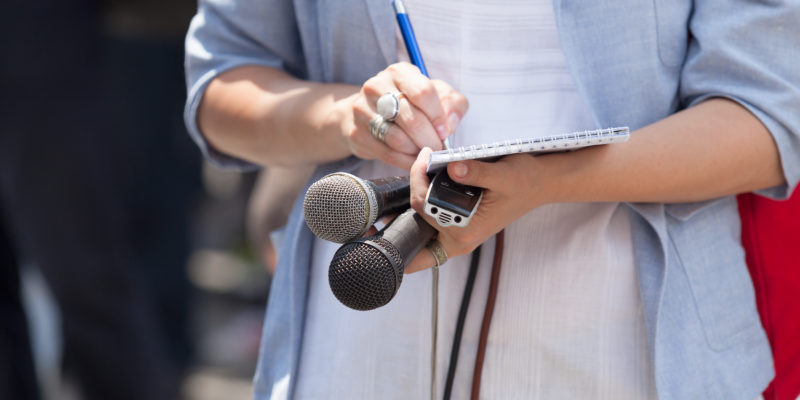 journalist taking notes during press conference.
